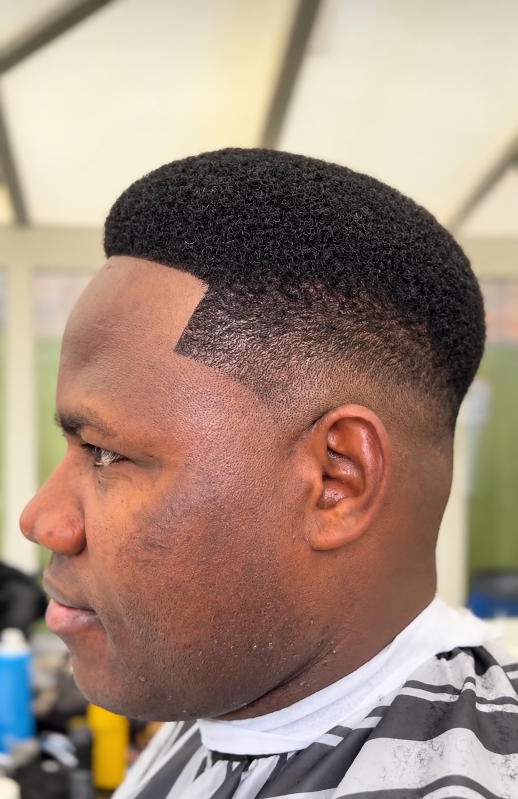 A short Afro haircut with a defined hairline and fade