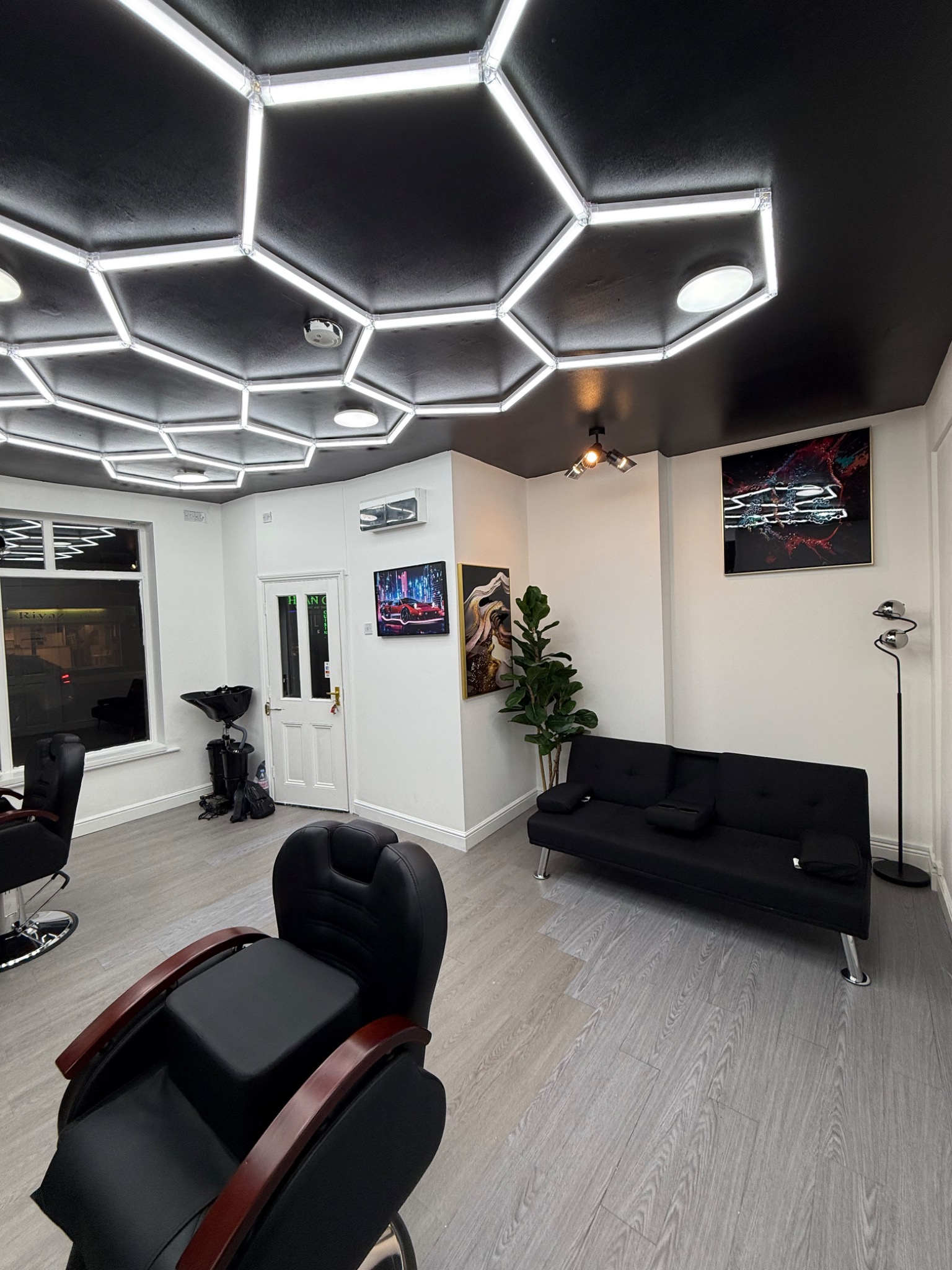 MBACUTZ studio with hexagonal ceiling lights, barber chairs and a black sofa